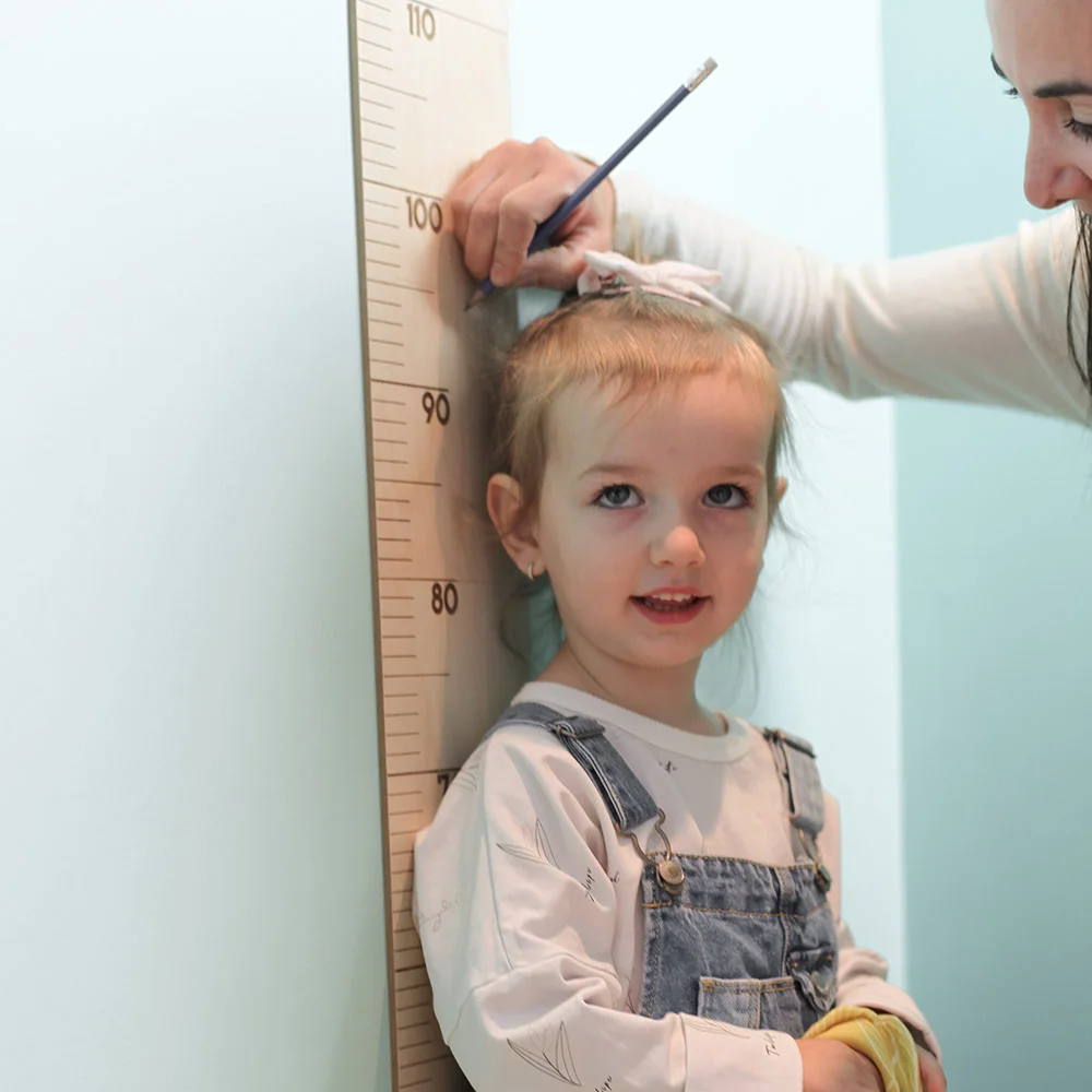 petite fille se fait mesurer par sa maman sur l'échelle de croissance