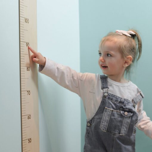 petite fille pointe sa grandeur sur l'échelle de croissance