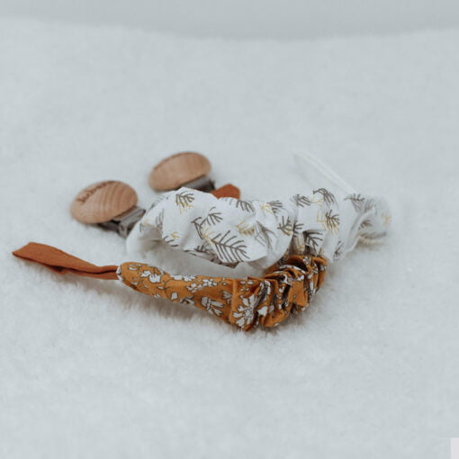 2 attaches en textile sur fond blanc - 1 : couleur blanche avec motif de feuilles et 2 : orange avec motif de fleurs