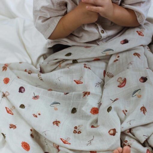 petit garçon aux main croisées assis avec la mousseline au motif d'automne