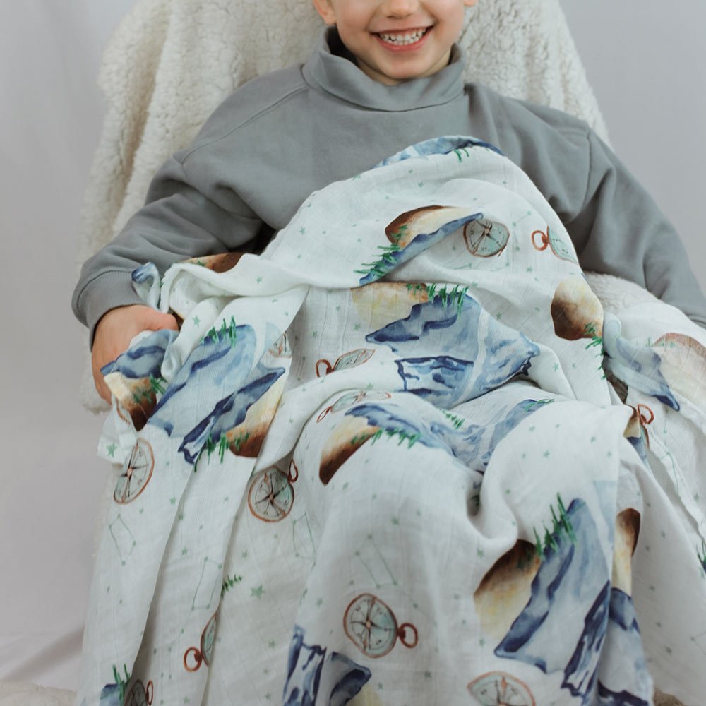 jeune garçon vêtu de gris sourit avec la mousseline à motif de montagnes, de lunes et de boussoles