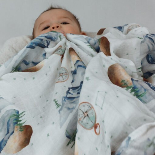 mousseline avec motifs de montagnes et de boussoles avec tête d'un bébé qui dépasse