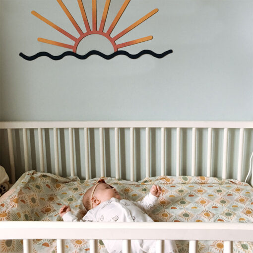 petite fille couché dans sa couchette avec doudou motif de soleil et un couché de soleil décoratif au mur